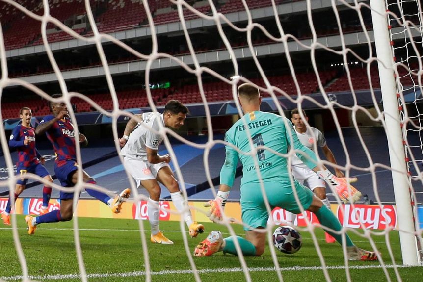 With the goal netting in the foreground, Philippe Coutinho kicks the ball toward goal as barcelona defenders surround him